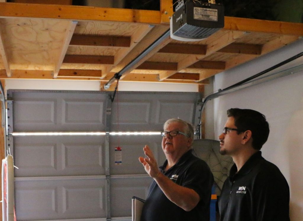 Two inspectors with our home inspection franchise opportunities inspect the inside of a garage.