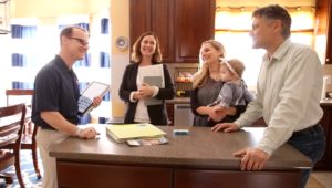 A WIN home inspector meets a real estate agent and their clients, a husband, wife and young child, in the customers’ potential home’s kitchen.