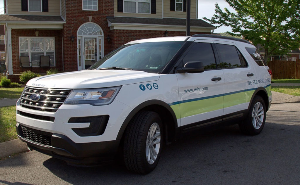 A WIN Home Inspection vehicle, used by franchisees as great marketing for home inspectors, is parked by the curb in front of a home.