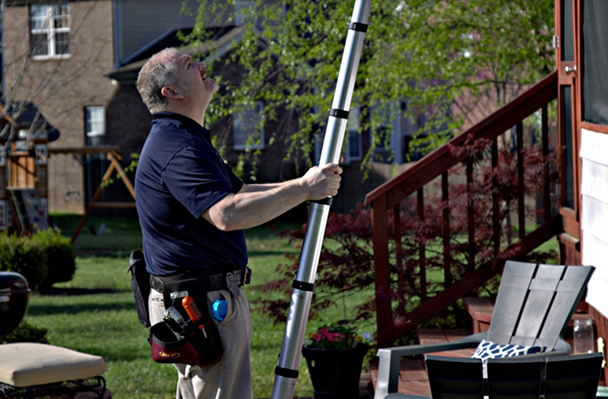 A WIN home inspector sets up a ladder against a client’s enclosed patio.