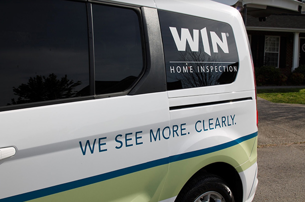 The WIN Home Inspection logo and tagline “We See More. Clearly.” on the back panels of a branded van.