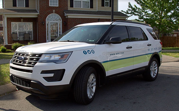 A WIN-branded SUV is parked in front of a home.