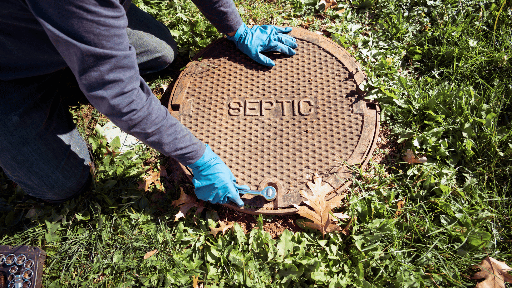 A septic inspector opening septic system tank.