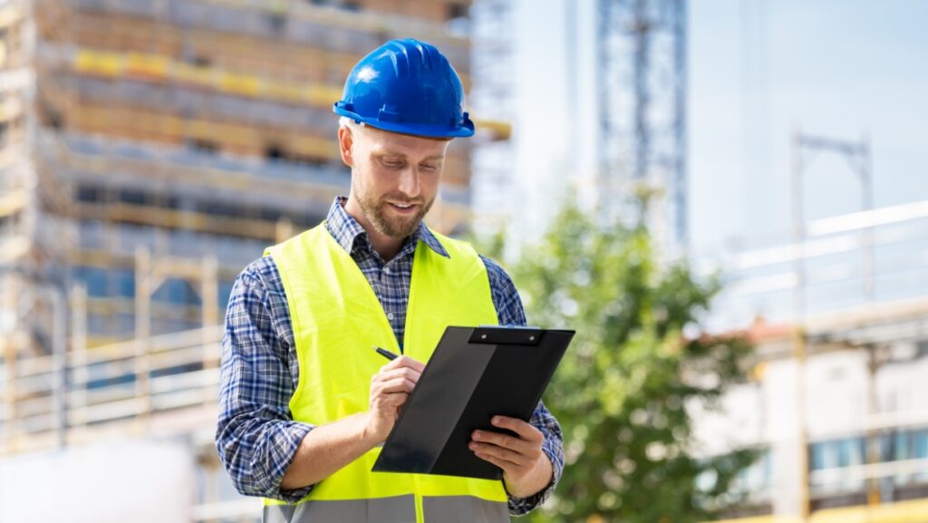 Building inspector with a hat and clipboard at a construction site