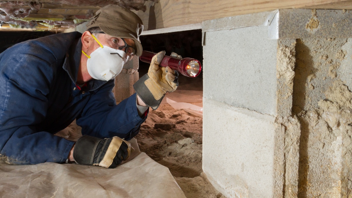 Home inspector looks for termites in residential home's crawl space