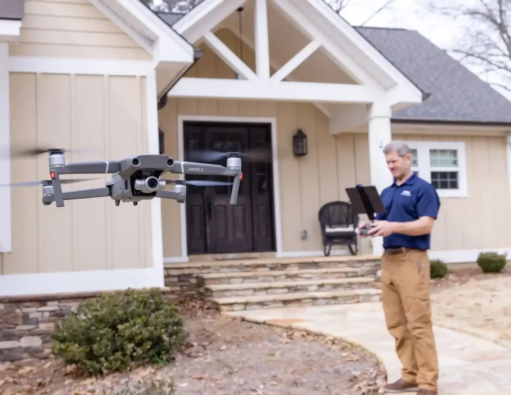 Flying drone with a home inspector in background