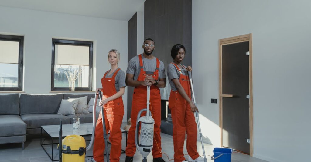Diverse cleaning team in red uniforms ready to sanitize a modern living room with vacuum and mop.