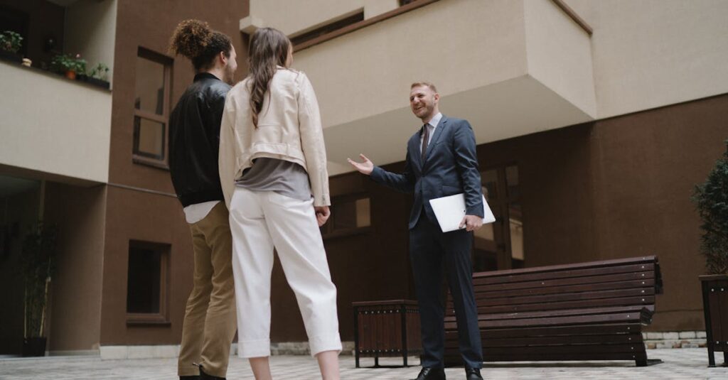 A realtor converses with a couple in a modern apartment courtyard.
